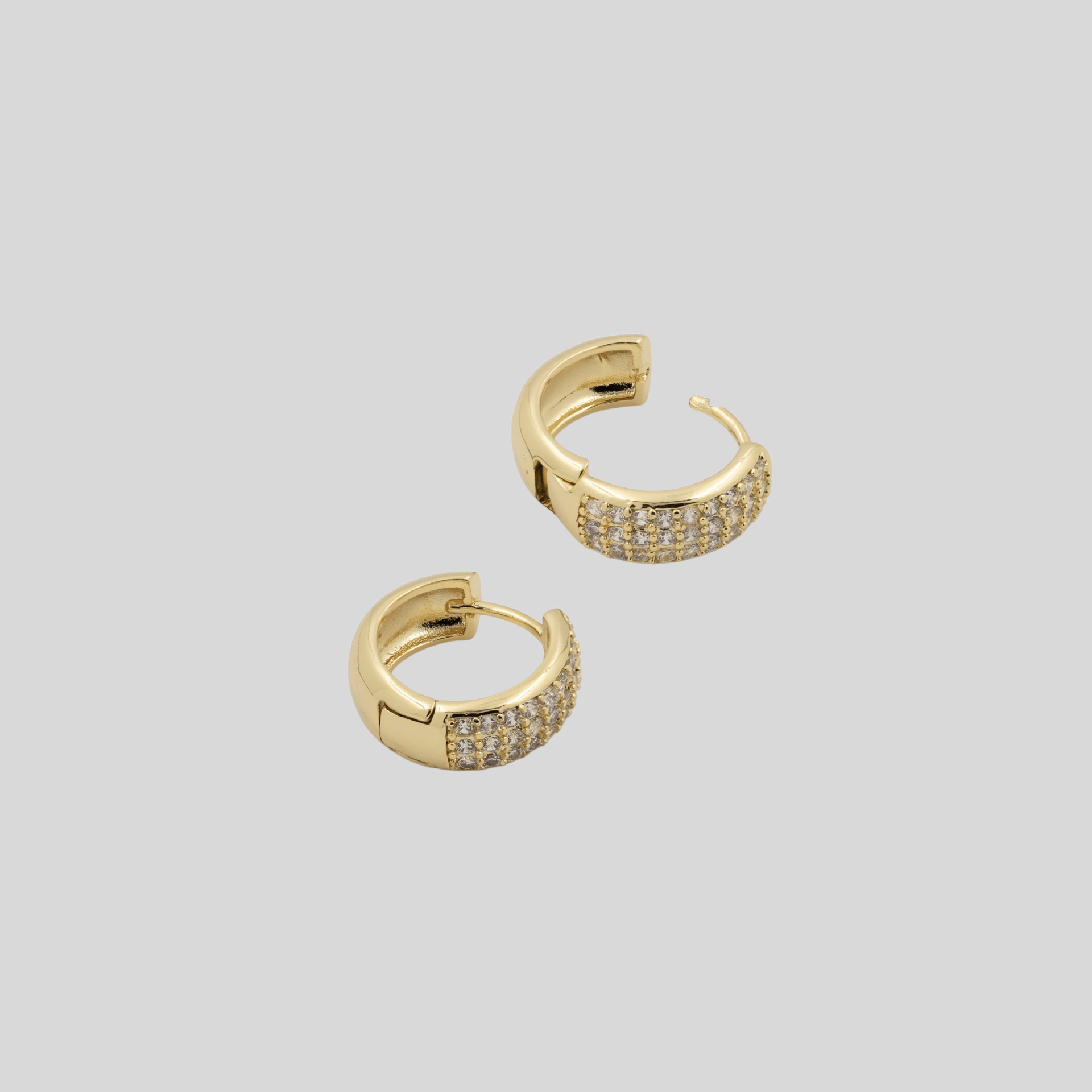 Gold hoop earrings with embedded stones on a light gray background