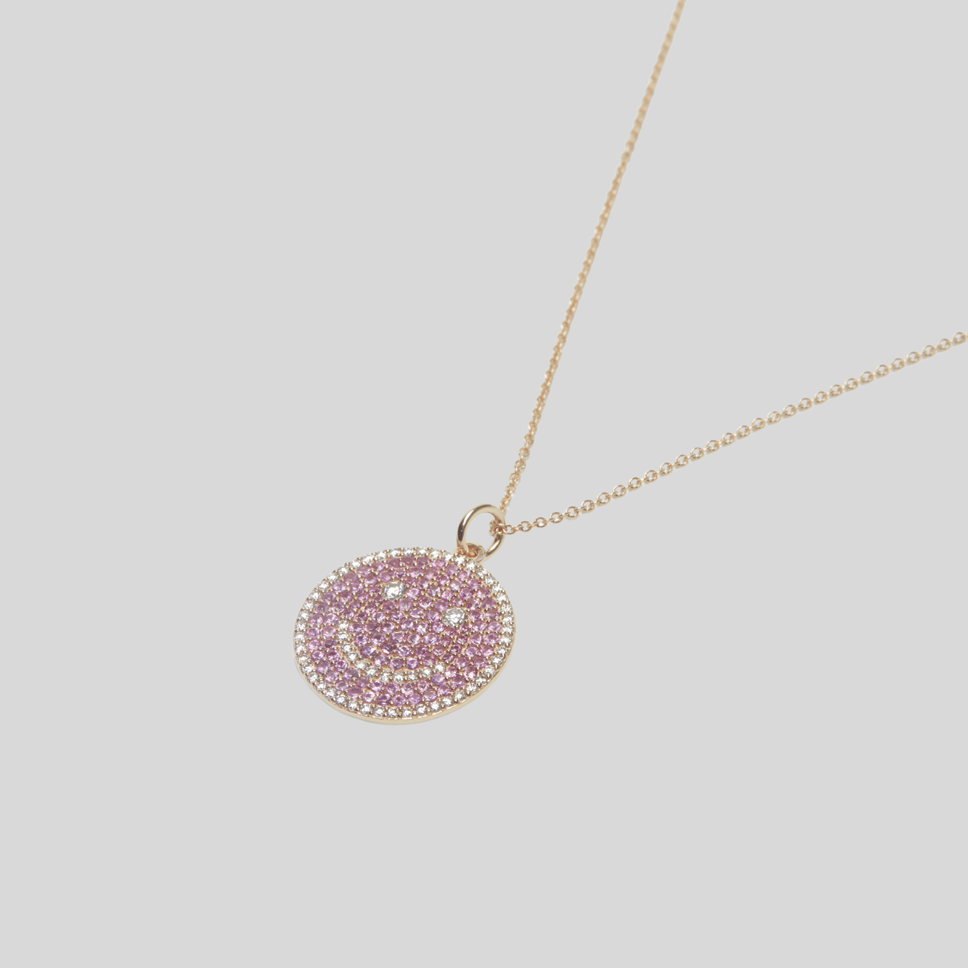Necklace with a pink circular pendant on a light gray background