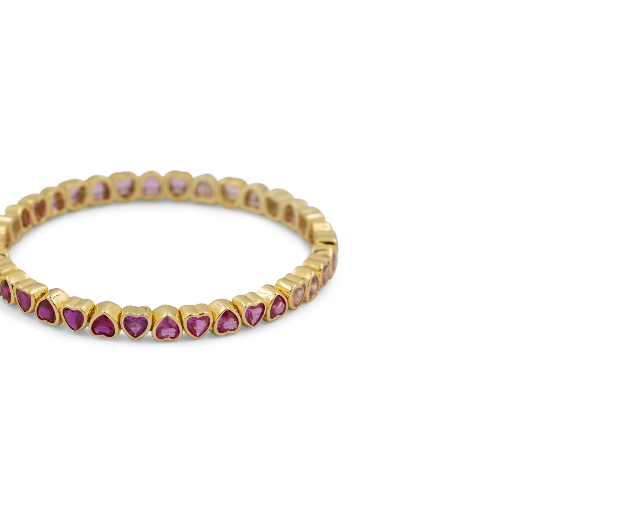 A gold eternity-style band bracelet featuring small heart-shaped pink gemstones set along the front, photographed on a clean white background.