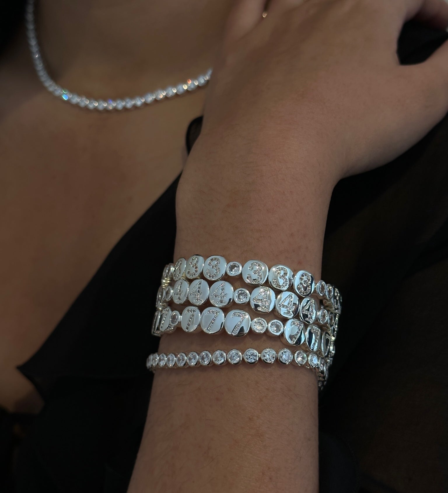 Close-up of a wrist wearing two silver bracelets with a blurred background