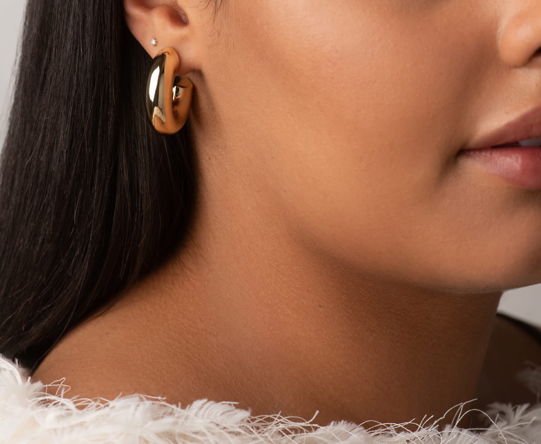Yellow gold chunky hoop earrings shown on model's ear, hinged clasp visible