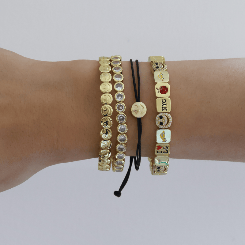 Wrist wearing multiple bracelets with various designs on a plain background