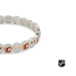 Close-up of white beaded bracelet with red and gold team logos and rhinestone details.