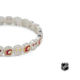 Close-up of white beaded bracelet with red and gold team logos and rhinestone details.