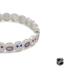 Close-up of white beaded bracelet with red and blue team logos and crystal detail.