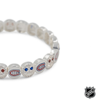 Close-up of white beaded bracelet with red and blue team logos and crystal detail.