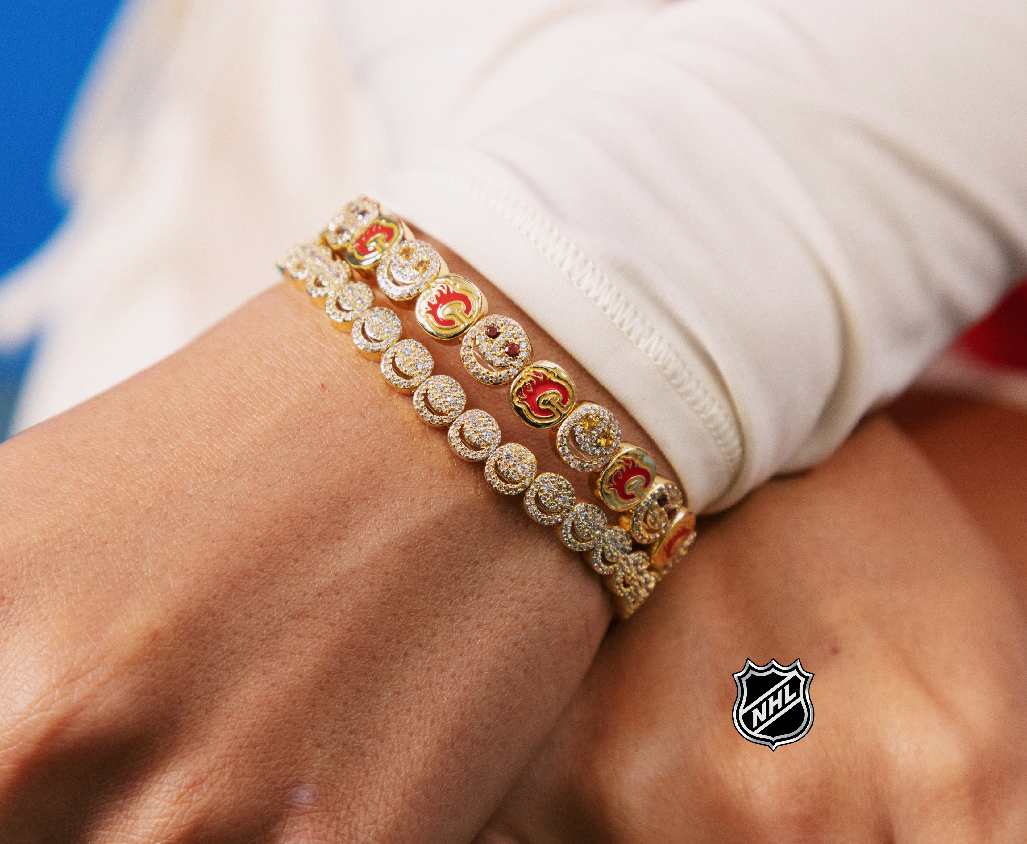 Gold-tone bracelet with circular logo charms and red enamel details
