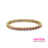 A yellow gold eternity bracelet featuring small heart-shaped purple gemstones set in a row, photographed on a clean white background.