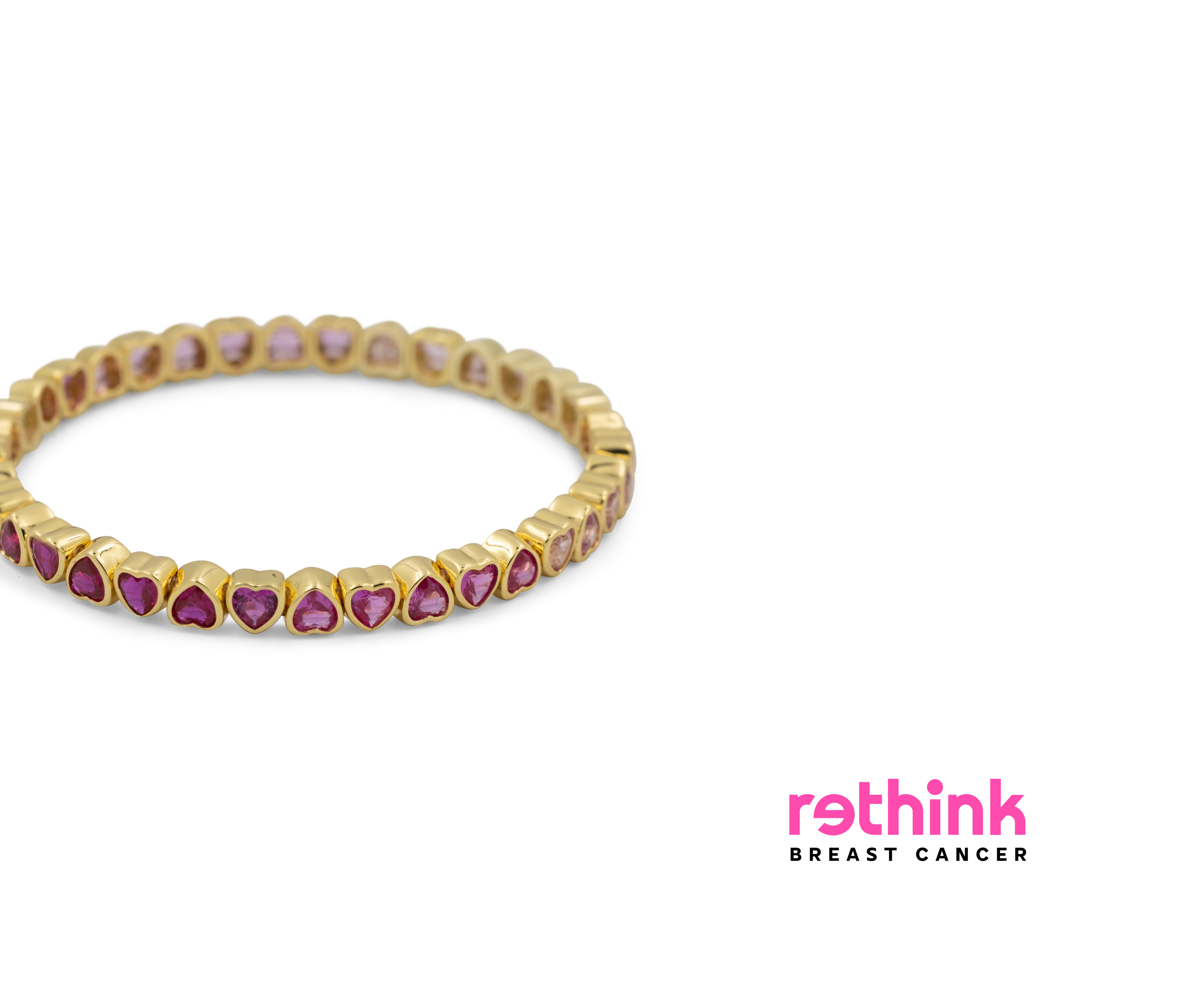 A gold eternity-style band bracelet featuring small heart-shaped pink gemstones set along the front, photographed on a clean white background.