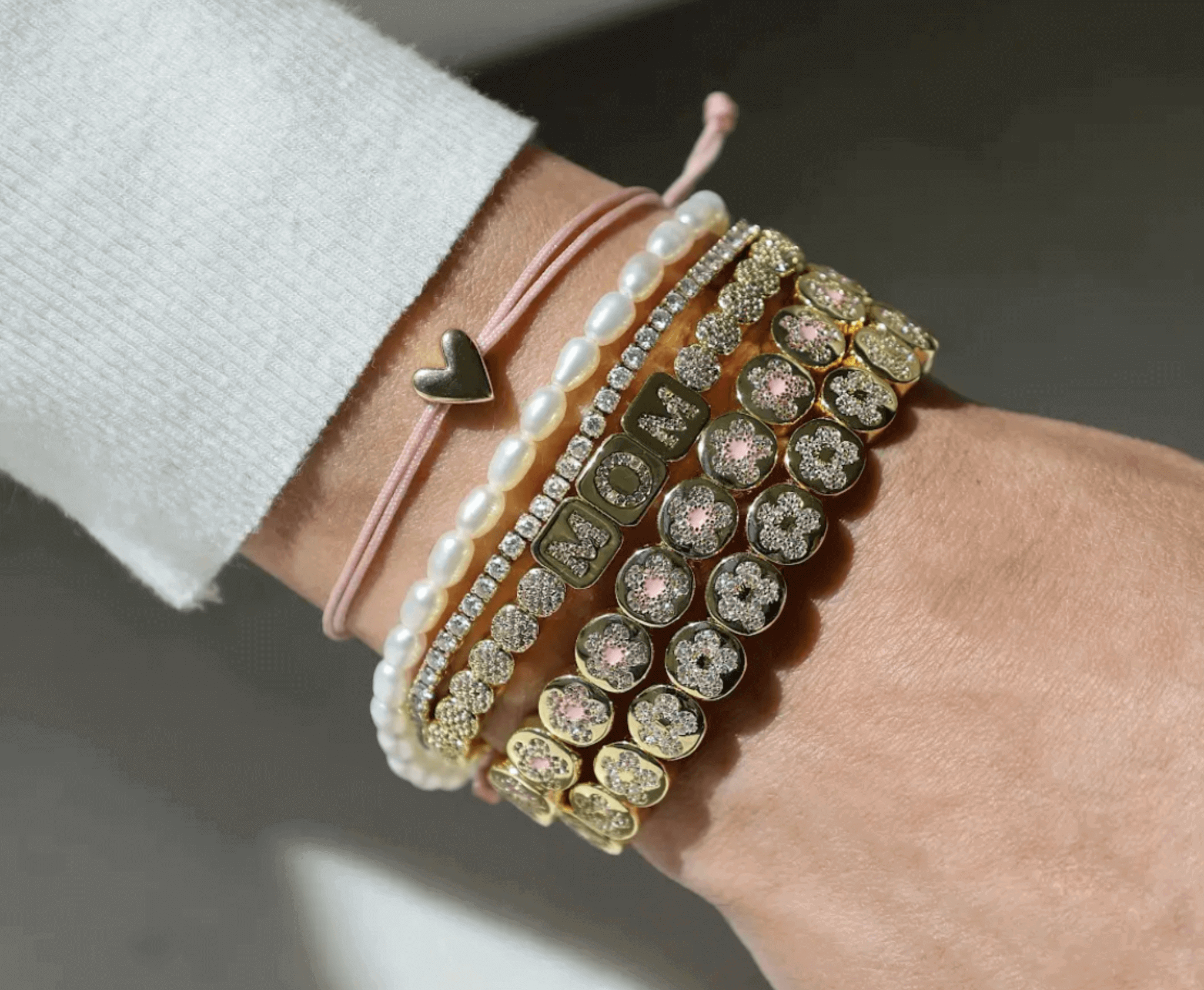 Close-up of a wrist wearing multiple bracelets with pearls and crystals.