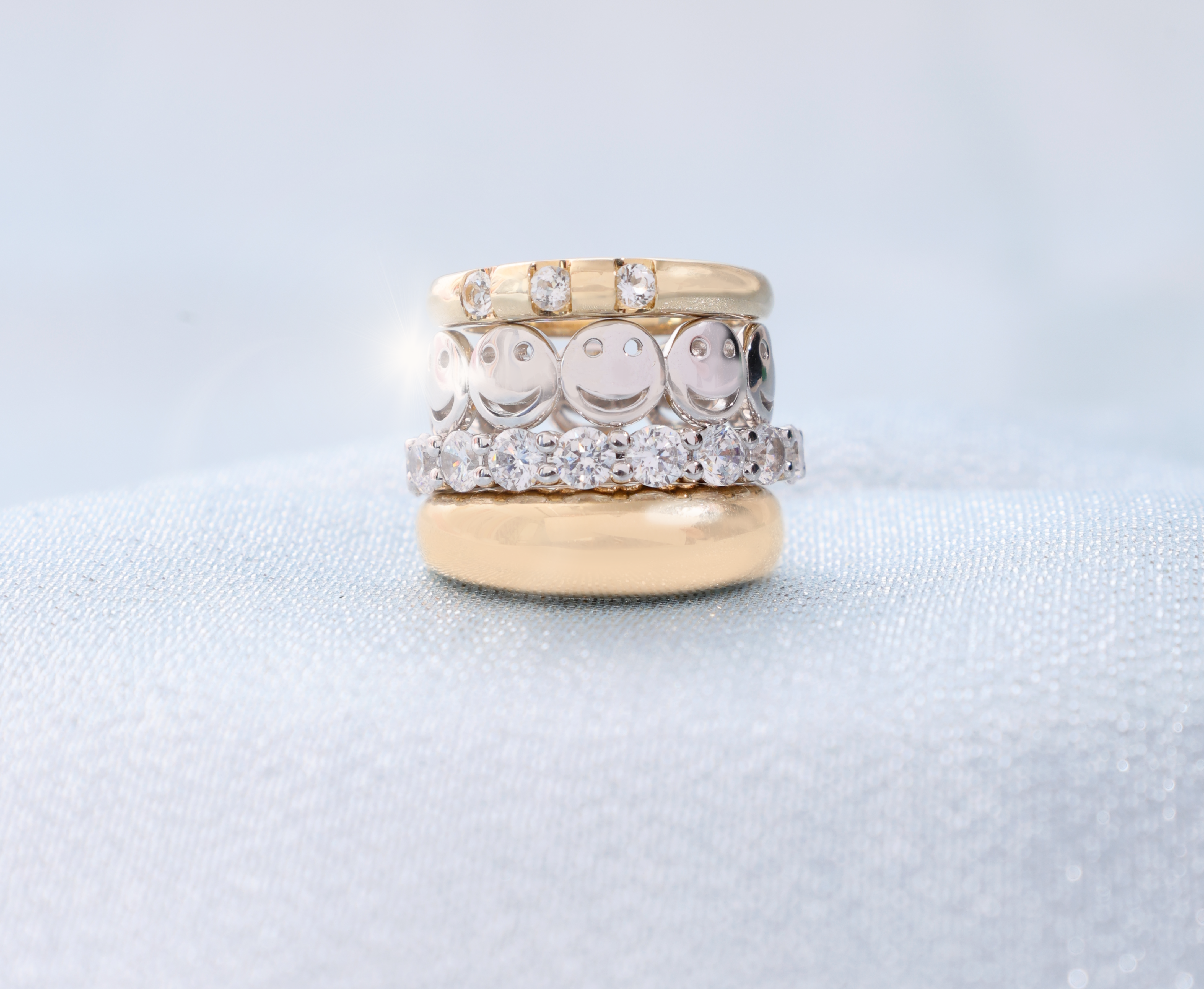 Stack of gold and silver rings on a light gray background