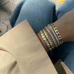 Close-up of a person's wrist wearing multiple bracelets on a blurred background