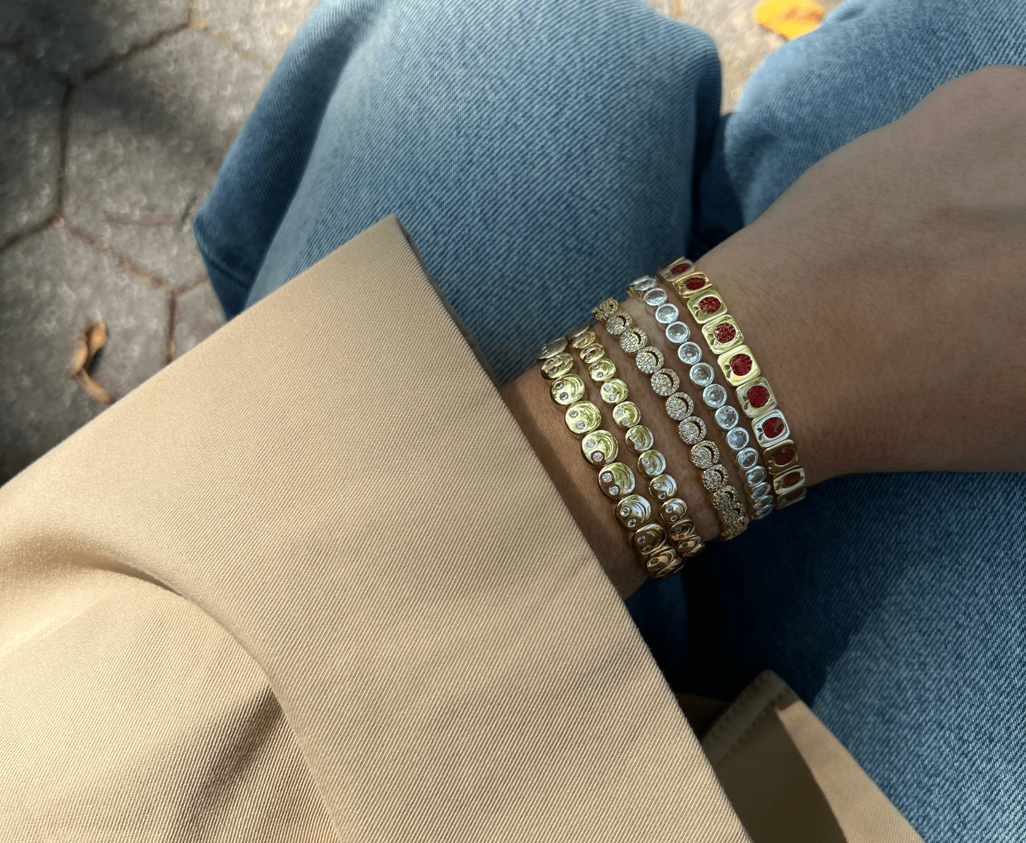 Close-up of a person's wrist wearing multiple bracelets on a blurred background