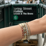 Close-up of a wrist with multiple charm bracelets in an urban setting