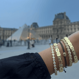 Gold bracelets on a wrist with a blurred background of a famous landmark